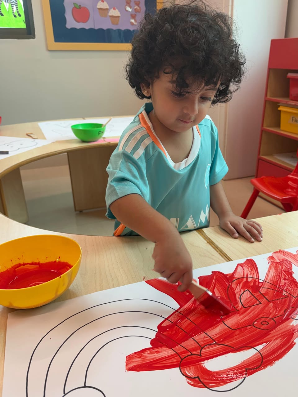 A child exploring red paint with a brush at Talking Tots